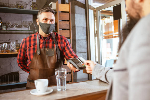 istock Waiter wearing a facemask while getting a contactless payment at a restaurant 1320062565