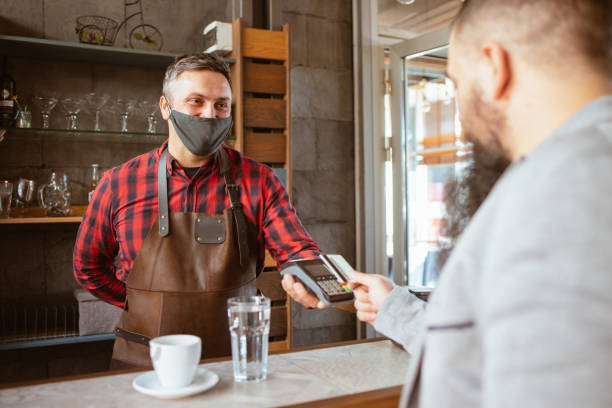 istock Waiter wearing a facemask while getting a contactless payment at a restaurant 1320063088