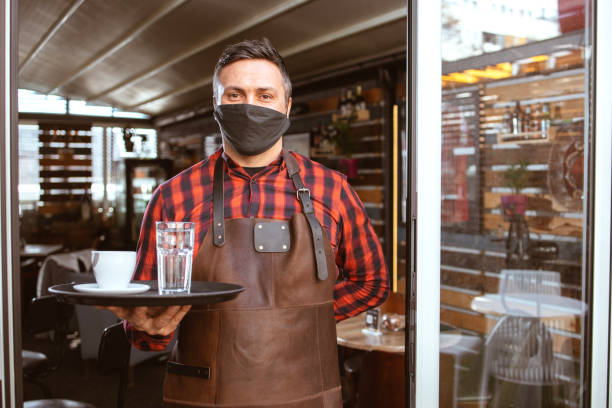 istock Waiter with protective face mask at the coffee shop door 1320063220