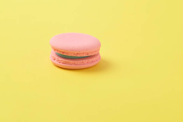 istock Pink french macaroons on bright yellow background 1320068165