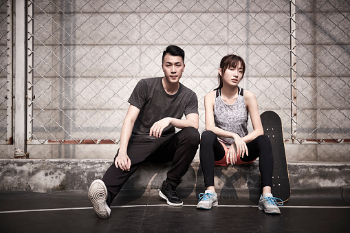 young asian adult man and woman resting relaxing outdoors after exercise