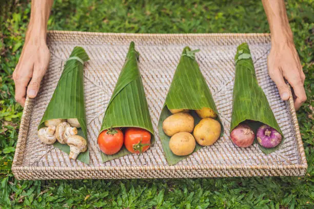 Photo of Eco-friendly product packaging concept. Vegetables wrapped in a banana leaf, as an alternative to a plastic bag. Zero waste concept. Alternative packaging