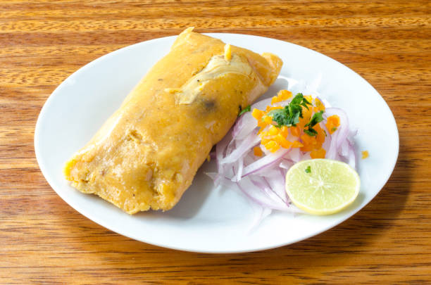 Peruvian tamale, traditionally eaten for breakfast on Sundays, made of corn and chicken and served with salsa criolla - onion salad. stock photo