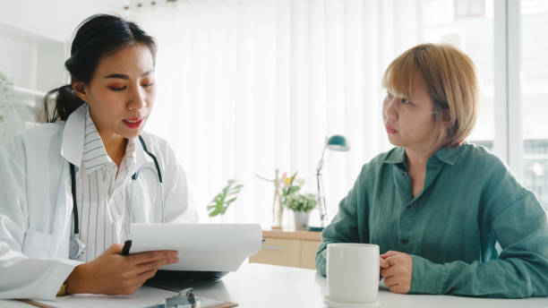 클립보드를 사용하는 젊은 아시아 여성 의사는 건강 클리닉의 책상에 앉아있는 소녀 환자와 결과 또는 증상에 대해 논의하는 좋은 뉴스 토크를 제공하고 있습니다. - customer therapy asking doctor 뉴스 사진 이미지