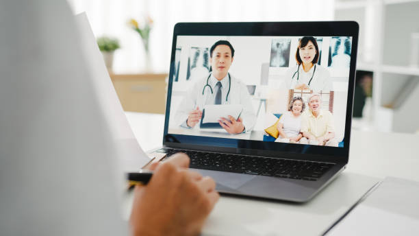 istock Young Asia lady doctor in white medical uniform with stethoscope using computer laptop talking video conference call with patient. 1320082290
