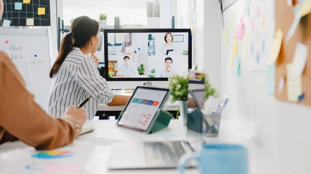 데스크톱을 사용하는 아시아 기업인은 새로운 일반 사무실에서 화상 통화 회의에서 계획에 대해 비즈니스 브레인 스토밍을 논의하는 동료에게 이야기합니다. - remote control 뉴스 사진 이미지