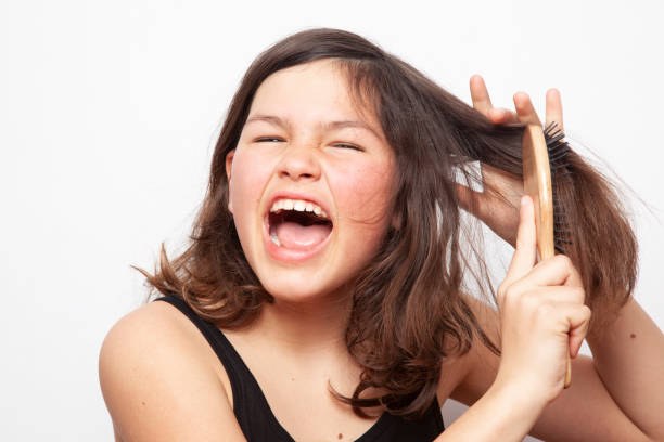 Teenager girl trying to comb her hair. The problem of teen stock photo