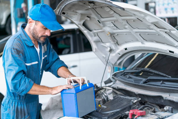 car repairs. auto services and small business concepts. a car mechanic is replacing the battery in an auto repair center. - car battery imagens e fotografias de stock