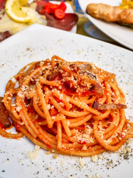 ein appetitliches und einladendes gericht von 'bucatini all'amatriciana' nach der römischen küche - vibrant color tomato vegetable pasta stock-fotos und bilder