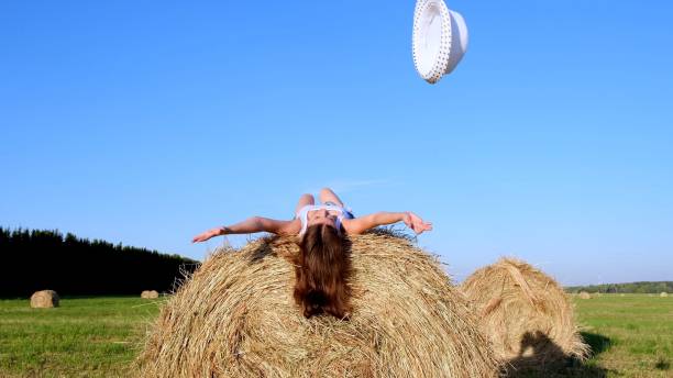 istock young female lies on a haystack and throws his hat. Rural area. freedom concept 1320097232