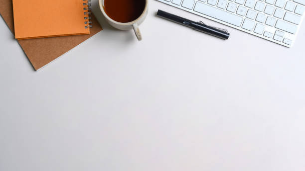 istock White office desk with keyboard, notebook, coffee cup and pen. 1320100130