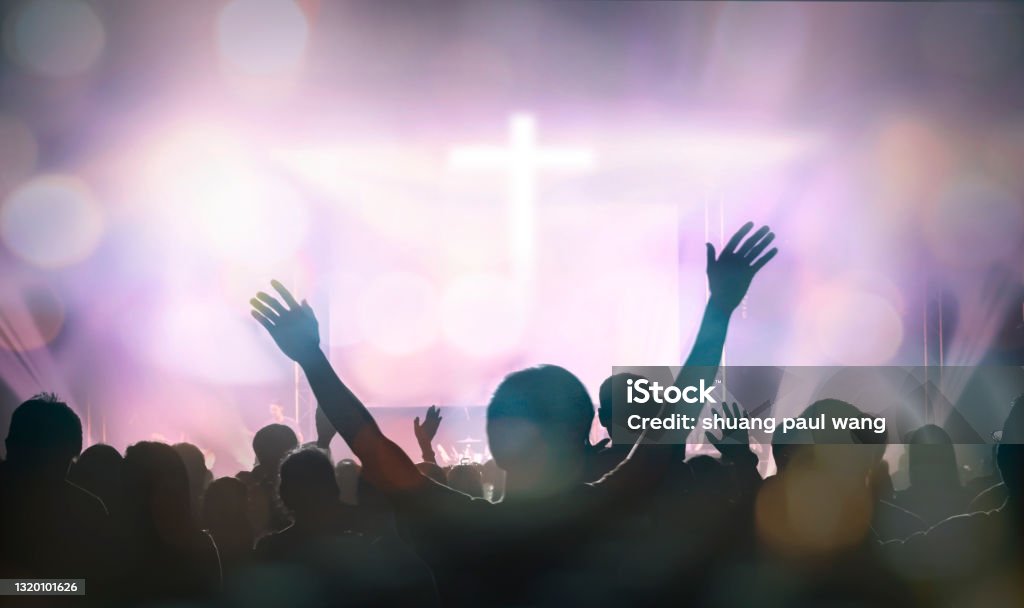 Christians raising their hands in praise and worship at cross background Church Stock Photo