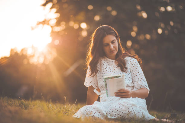 istock Woman reading book in the nature. Sitting on grass. 1320102996
