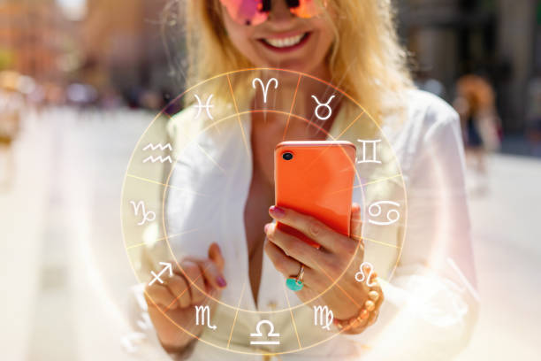 Concept of reading daily horoscopes on the phone Concept of reading daily horoscopes on the phone; woman holding a phone and reading her daily horoscope woman fortune telling stock pictures, royalty-free photos & images