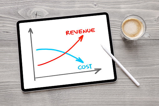 Photo of tablet computer on desk with a graph of revenue and cost drawn on the screen