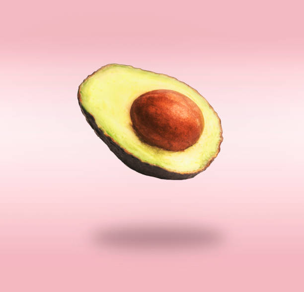 istock Flying half avocado with seed at pink background with shadow. 1320103148
