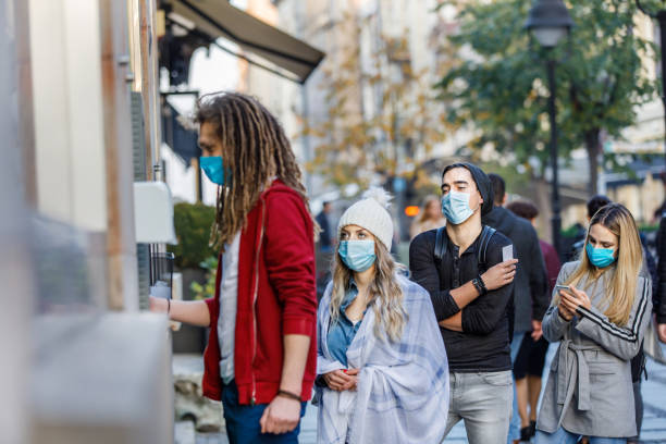 foto orang anjajar dengan masker wajah pelindung menunggu atm. - slot viral potret stok, foto, & gambar bebas royalti