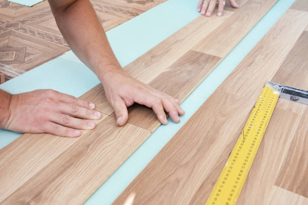 istock Wood laminate flooring installation: Laminate flooring installers are installing laminate hardwood planks over a soundproofing underlayment, insulation. 1320104440