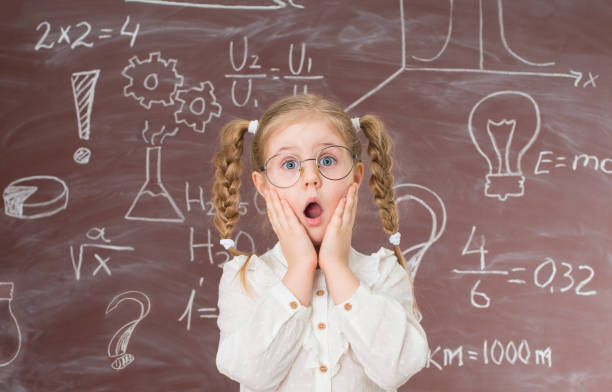 Funny shocked  little girl in glasses near chalkboard full of signs and formulas. Education concept. Funny shocked  little girl in glasses near chalkboard full of signs and formulas. Education concept. blackboard child shock screaming stock pictures, royalty-free photos & images