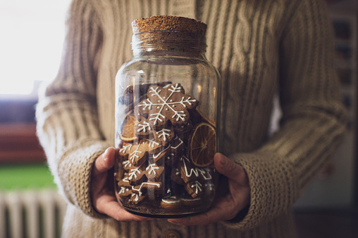 Unrecognizable woman holding Christmas gingerbread cookies in the jar.