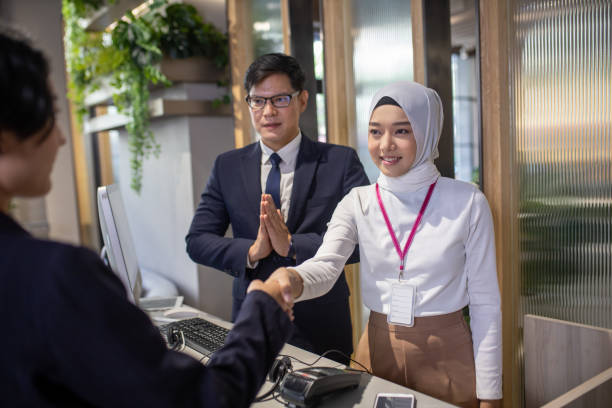 istock Young Asian hotel receptionist at workplace. Picture of two receptionists at work 1320105951