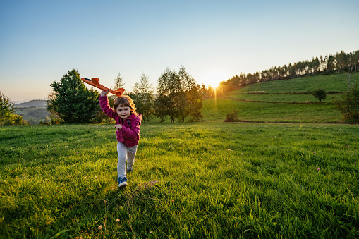 Girl throwing airplane in nature