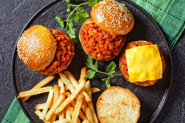 homemade BBQ Sloppy Joe sandwiches with french Fries on a black plate, flat lay, close-up, american cuisine