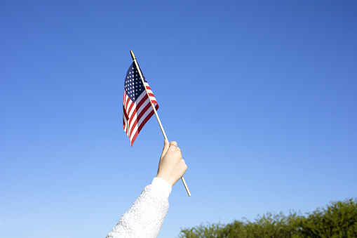 July 4, Independence Day in America. Memorial Day in America. American flag in hand against the blue sky.Holiday concept.