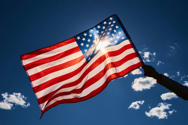 istock Waving usa flag in hand against blue sky. 1320108141