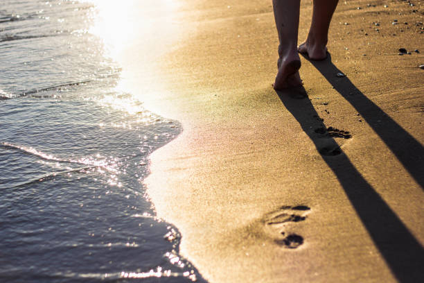 istock Beach travel - legs walking on sandy beach leaving footprints in the sand 1320111201