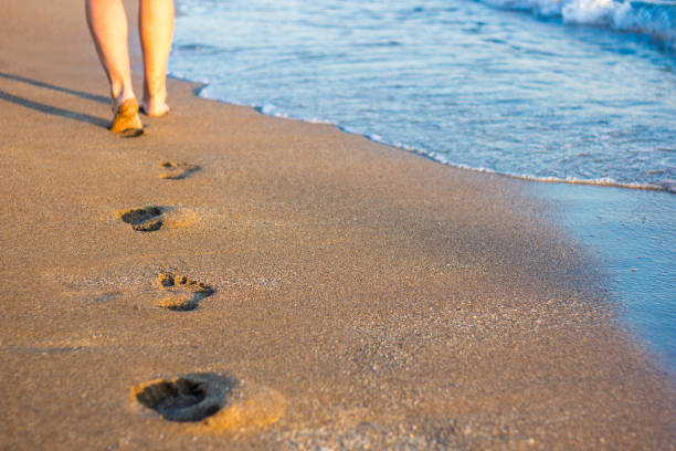 istock legs, footprints in the sand and sea wave 1320111226