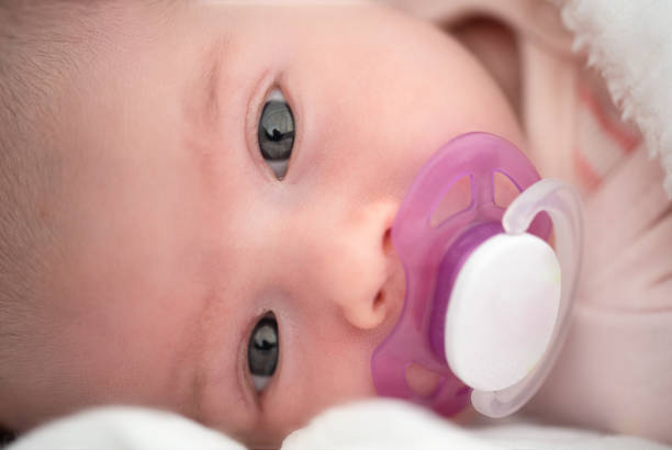 istock Newborn baby is lying on its side with white soother in mouth 1320112430