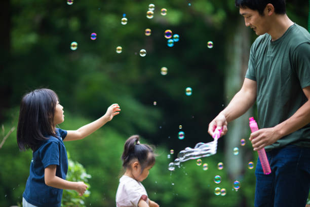 istock A father making bubbles for his daughters to play with 1320114766