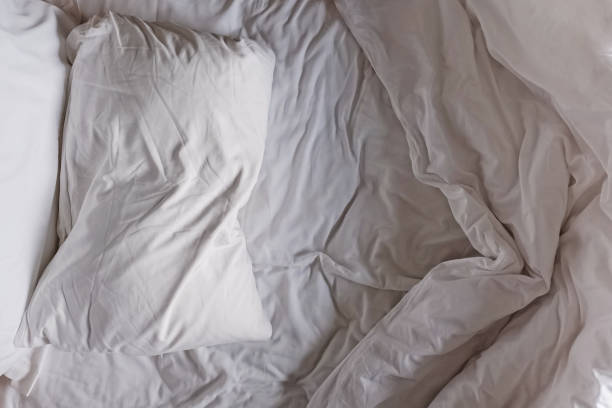 istock Top view of the unmade white bed sheet and pillow 1320118094