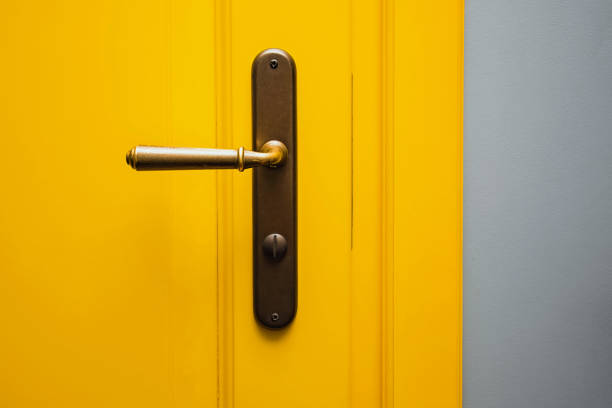 istock Yellow door with a bronze door handle close-up. 1320118363
