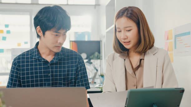 istock Young coworker asia creative businesspeople manager discuss project compare point in paperwork and laptop on table working and communicate together sitting on office desk. 1320118656