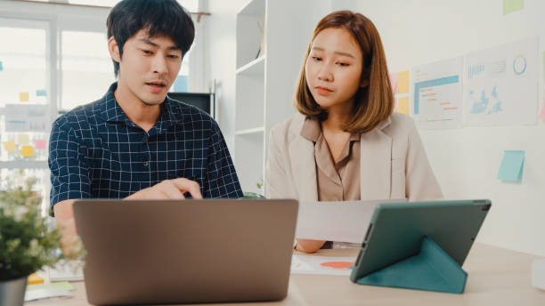 istock Young coworker asia creative businesspeople manager discuss project compare point in paperwork and laptop on table working and communicate together sitting on office desk. 1320118733