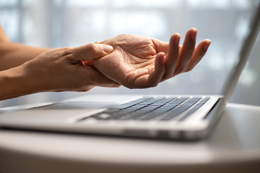 A woman has finger and hand pain after using a computer for a long time. Pain in wrist while using laptop, carpal tunnel syndrome.