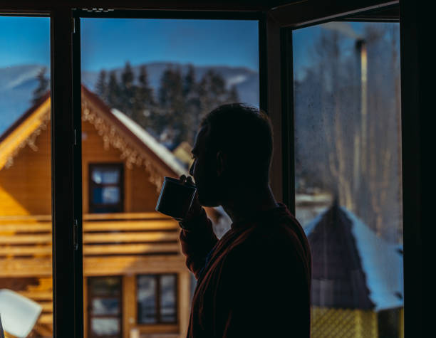 istock Cottage. The man in the window is drinking a hot drink. 1320121143