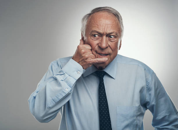 istock Shot of a senior businessman standing alone against a grey studio background and making a cellphone hand gesture 1320123921