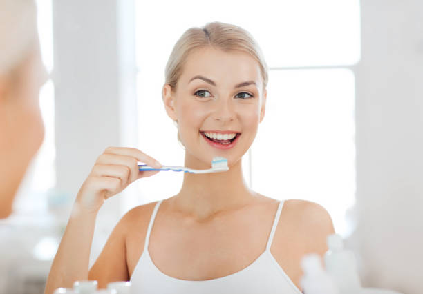 istock woman with toothbrush cleaning teeth at bathroom 1320124373