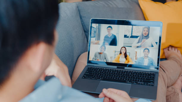 istock Young Asia businessman using laptop talk to colleagues about plan in video call meeting while work from home at living room. 1320125421