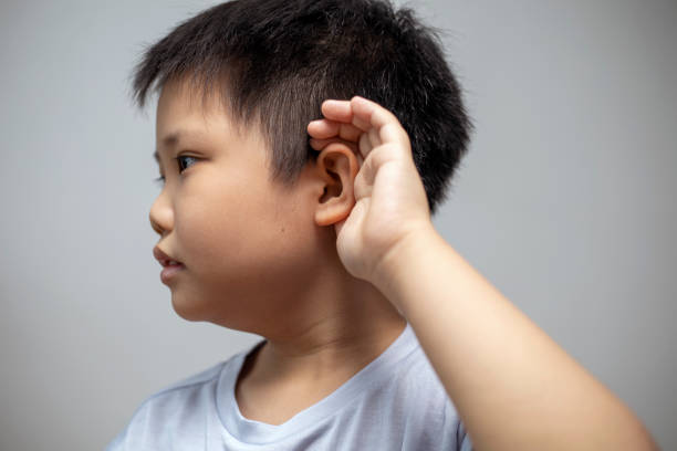 istock Boy With Hand By Ear Against gray Background 1320125938