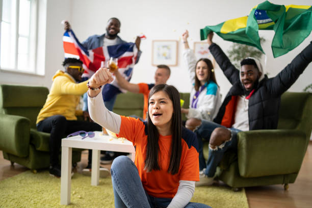 a group of friends wave flags and arms in celebration watching the television - british flag freedom photography english flag imagens e fotografias de stock