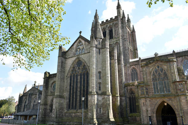 portrait image of magnificent hereford cathedral towers on a bright sunny day in spring with blue sky in background and green trees infront - uk cathedral cemetery day imagens e fotografias de stock