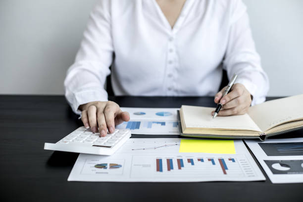 istock An accounting businesswoman pressing the white calculator and taking notes in her notebook, she was examining the company's financial accounts from the documents provided by the finance department. 1320130601