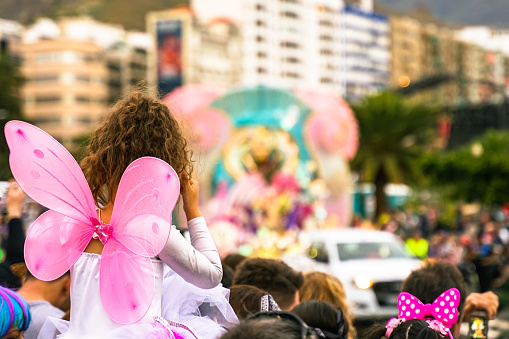 Gente mirando la fiesta de carnaval. Chica bonita vestida como un ángel rosa en una fiesta de carnaval. Fondo desenfocado - Imagen photo