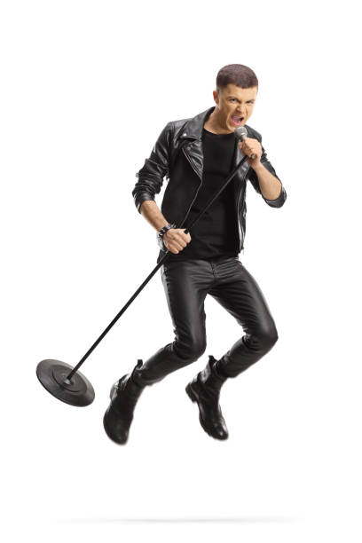 istock Young male rock singer jumping with a microphone 1320133455