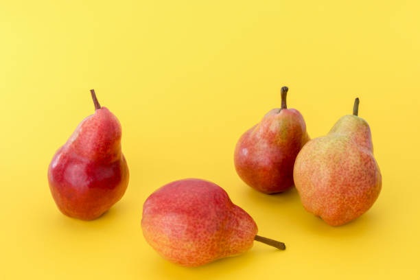 istock four whole red pears isolated on yellow 1320134428