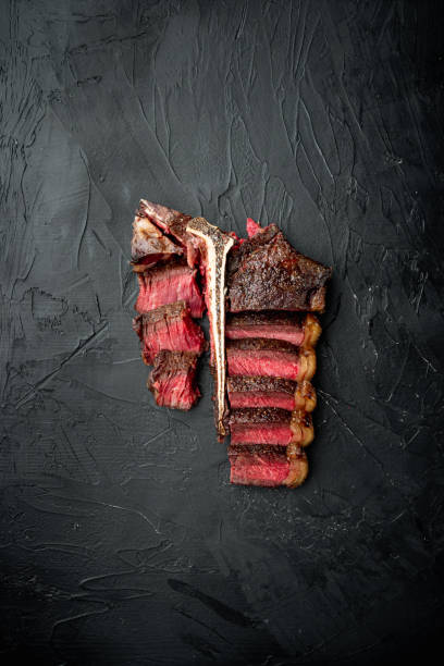 istock Sliced medium rare grilled Beef steak, t bone or porterhouse cut, on black stone background, top view flat lay, with copy space for text 1320134532